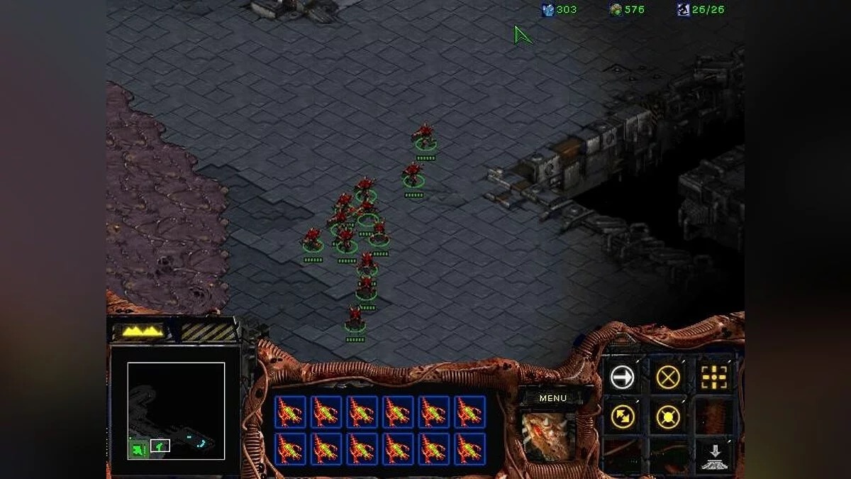 Capture d'écran d'une carte du jeu StarCraft. Un groupe d'unités Zerg rouges se tient sur un terrain en dalles de pierre, avec du creep mauve s'étendant le long du bord gauche et des ruines industrielles à droite. L'interface classique de StarCraft borde le bas de l'écran&nbsp;: minicarte en bas à gauche, portraits d'unités au centre, panneau d'actions à droite.